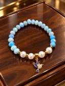 Pulsera confeccionada a mano con cristales celestes luminosos, elegantes perlas blancas y un precioso dije de colibrí.  Una joya práctica, elástica y perfecta para elevar tu estilo diario.