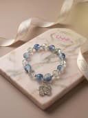 Pulsera elaborada a mano con hermosas cuentas azules destellantes, cristales facetados traslúcidos y un deslumbrante dije de flor repleto de brillo. Su diseño en elástico  la hace súper cómoda y práctica para acompañarte siempre.
